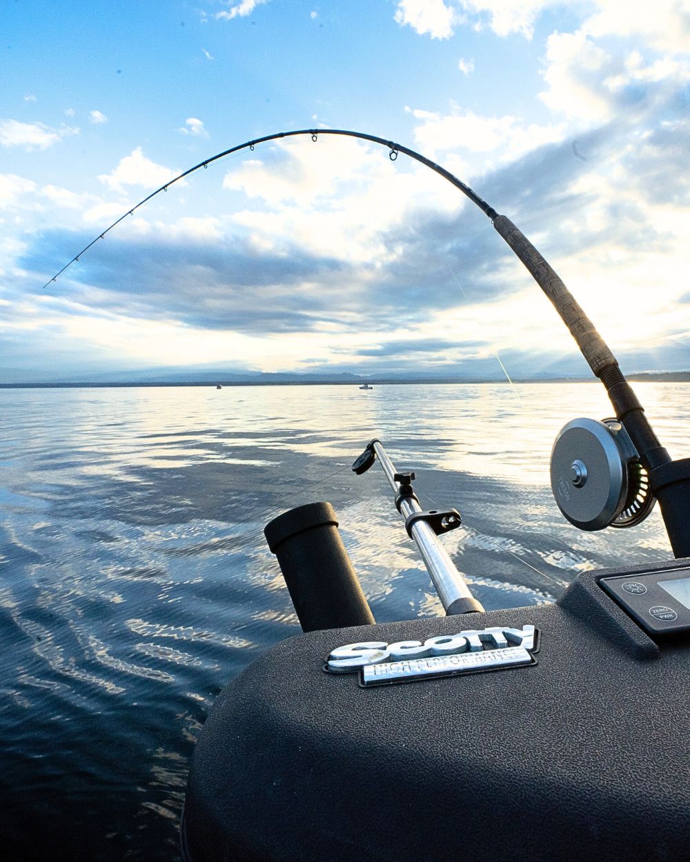Cool photo of a fishing rod attached to a boat. The rod is bending with the line cast.